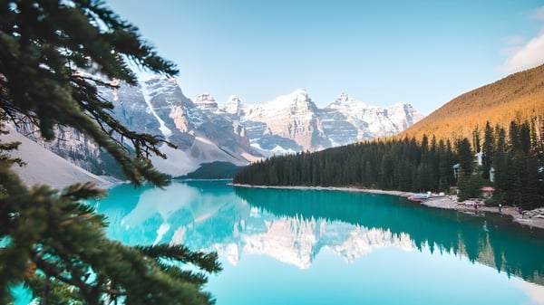 Un claro lago alpino con montañas cubiertas de nieve y un bosque en primer plano cerca de la Abbey Park High School.