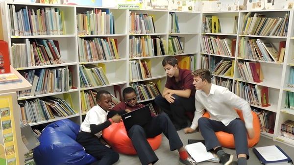 Estudiantes de la Abbotsford Christian School están sentados en coloridos puff en la biblioteca entre estanterías llenas de libros.