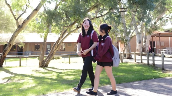 Dos estudiantes de la Aberfoyle Park High School están juntas en un entorno similar a un parque con mucha vegetación y árboles.