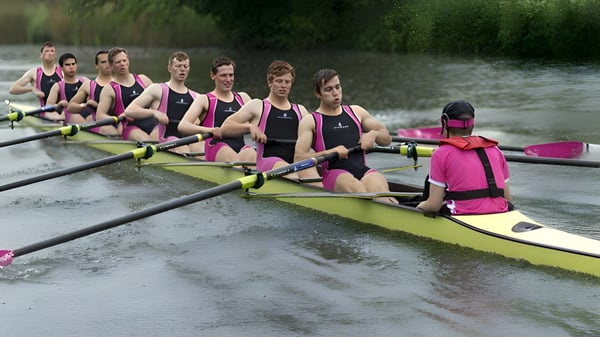 El equipo de remo de la Abingdon School entrena en un río rodeado de vegetación verde.