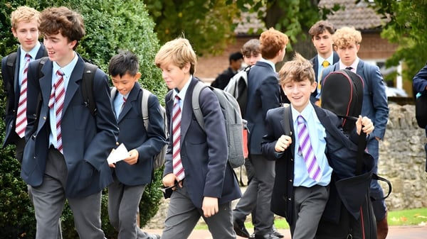 Un grupo de estudiantes de la Abingdon School camina juntos por un camino rodeado de plantas verdes.
