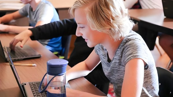 Una estudiante de la Accelerated School trabaja concentrada en un portátil en el aula con otros estudiantes.