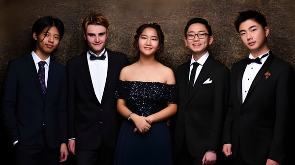 Un grupo de cinco estudiantes vestidos formalmente posan frente a un fondo oscuro en el ACG Parnell College.