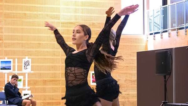 Una mujer en un vestido negro con plumas se presenta en el escenario de ACG Tauranga.