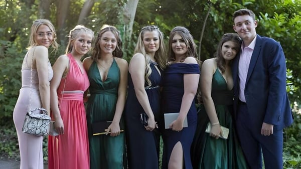 Un grupo de personas bien vestidas está de pie juntas en un área exterior verde de la Ackworth School.