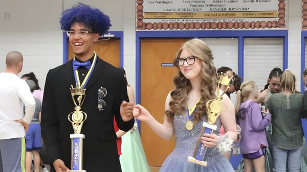 Dos estudiantes de la Acorn High School sostienen trofeos en una premiación en la escuela.