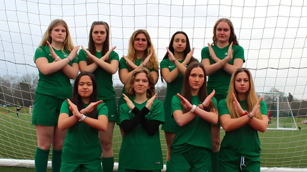 Un grupo de alumnas con uniformes verdes está frente a la portería en el campo de fútbol de la ACS International School Cobham.