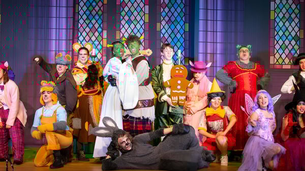 Alumnos de la ACS International School Cobham realizan una colorida representación teatral frente a un fondo de vitral.