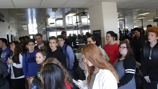 Estudiantes de Adrian High School llenan un pasillo concurrido con carteles en las paredes.