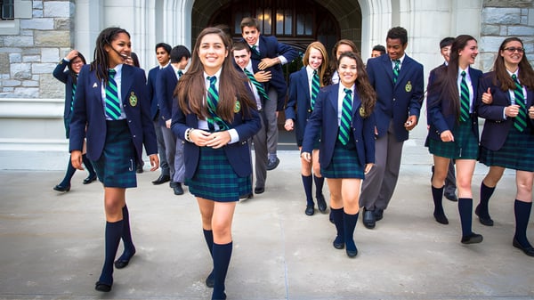 Estudiantes del Albert College caminan frente a un edificio de piedra en el campus.
