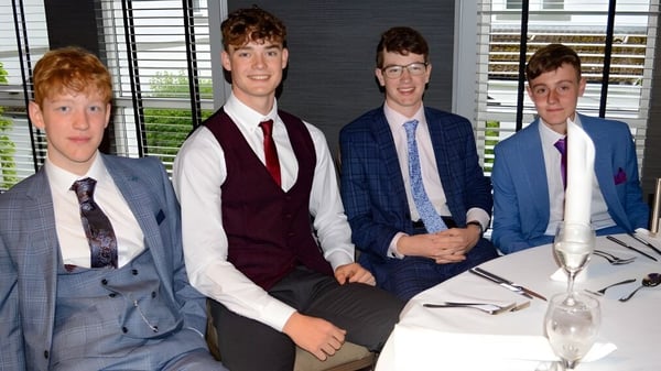 Cuatro estudiantes de la Albyn School están sentados en ropa formal en una mesa en una oficina con una ventana al fondo.