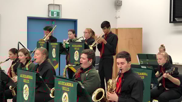 Un grupo de músicos de la Alexandra Hills State High School se presenta en uniformes en el escenario.