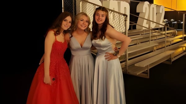 Tres alumnas de la All Saints High School Calgary posan juntas en una tribuna al aire libre.