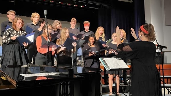 Estudiantes de la Allendale Columbia School se presentan juntos con instrumentos y partituras en un escenario.