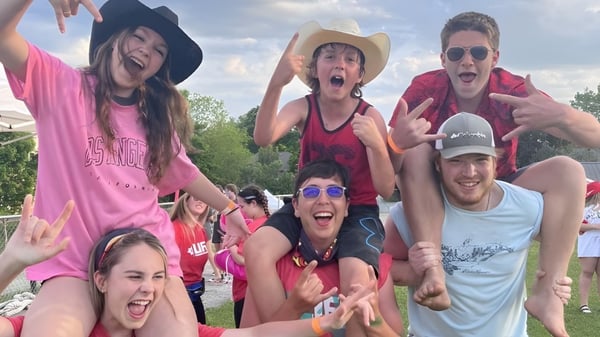 Un grupo de estudiantes de la Almonte & District High School muestra poses vibrantes al aire libre frente a un fondo verde.
