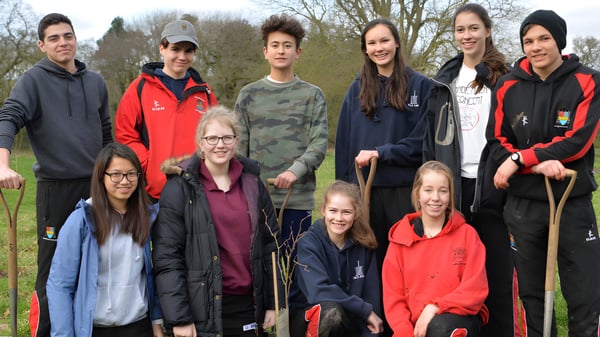 Un grupo de estudiantes del Ampleforth College está reunido en el exterior frente a árboles y áreas verdes.