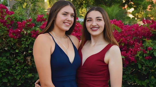 Dos estudiantes frente a un jardín exuberante con flores rojas en el terreno del Anaheim Union High School District.