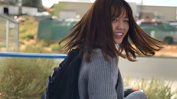 Una estudiante de la Apple Valley Christian School sonríe en un campo de hierba con edificios al fondo.