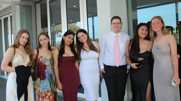 Un grupo de personas está frente al edificio de vidrio de la Applecross Senior High School.