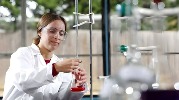 Una mujer con bata de laboratorio blanca realiza un experimento en el laboratorio de la Archbishop's School.
