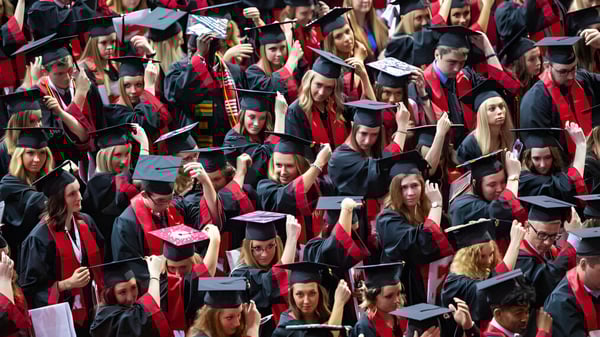 Un gran grupo de graduados de Ardscoil Phadraig en togas rojas se reúne para la ceremonia de graduación.