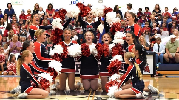 Un grupo de animadoras de la Arendell Parrott Academy realiza una presentación en la cancha de baloncesto frente a numerosos espectadores.