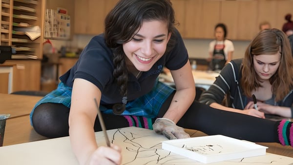 Una estudiante de la Argyle Secondary School está sentada concentrada en la mesa y dibujando.