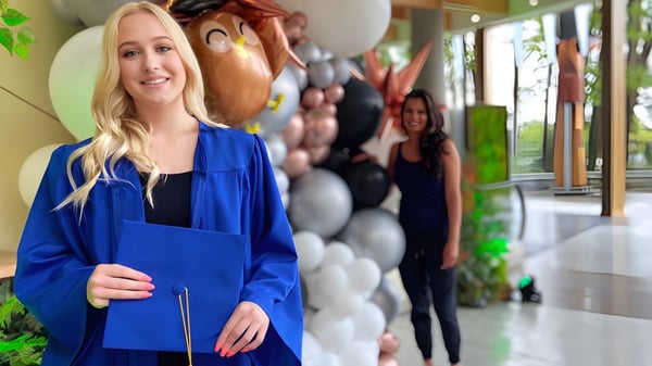 Una estudiante está en el pasillo con globos de colores de fondo en el campus de la Argyle Secondary School.