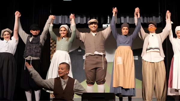Estudiantes de la Arizona Lutheran Academy realizan una obra de teatro en un escenario con fondo oscuro.