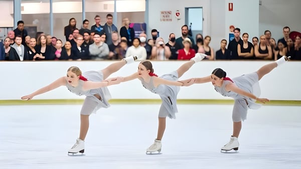 Estudiantes de la Armadale Senior High School realizan juntas una actuación sincronizada de patinaje artístico en la pista de hielo frente a un público.