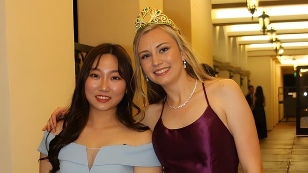 Dos estudiantes de la Arroyo Pacific Academy posan en el pasillo con luces decorativas de fondo.