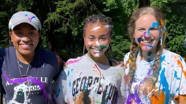 Tres estudiantes con colores brillantes en la cara y la ropa están en el terreno de la Asheville School.