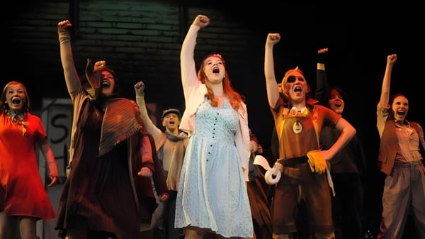 Estudiantes del Ashland School District realizan una obra de teatro en un escenario con luz tenue.