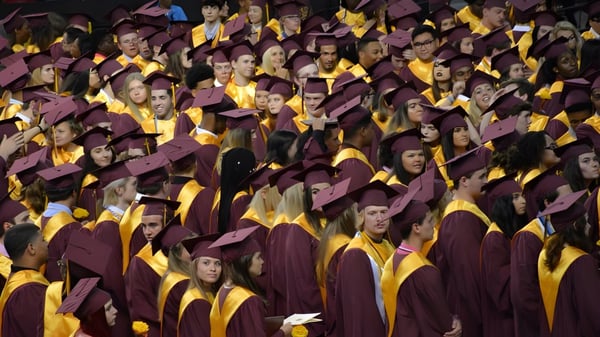 Los graduados de la Atherton State High School se reúnen durante la ceremonia de graduación en sus togas rojas y amarillas.