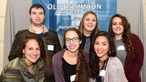 Un grupo de estudiantes sonríe frente a una pancarta de Old Dominion University en el campus de la Atlantic Shores Christian School.