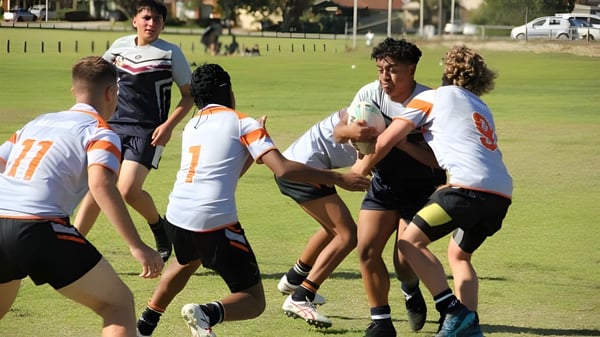 Alumnos y alumnas del Atwell College participan en una actividad deportiva en un campo verde.