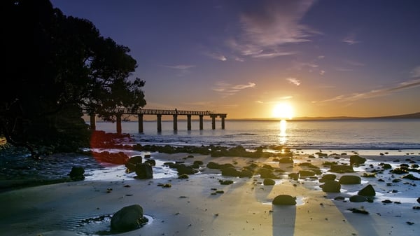 Un muelle de madera se extiende al atardecer en aguas tranquilas cerca de la Auckland Grammar School.