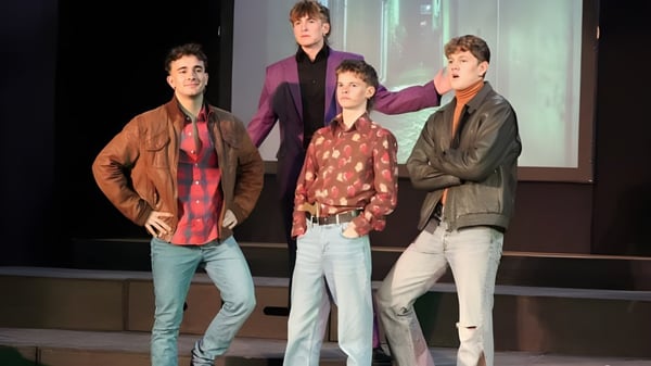 Cuatro alumnas y alumnos de la Austin Friars School están juntos en un escenario frente a un fondo oscuro.