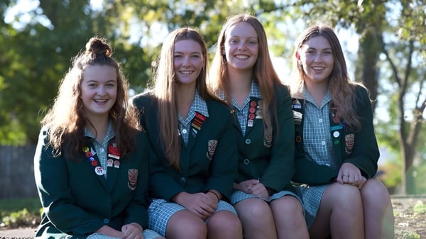Alumnas de la Avonside Girls' High School están sentadas al aire libre juntas y rodeadas de naturaleza verde.