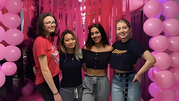 Cuatro estudiantes posan juntas en una escena festiva con globos de colores en el campus de la A.Y. Jackson Secondary School.