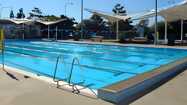 La gran piscina en el espacio exterior del Ballajura Community College está rodeada de áreas de descanso sombreadas y árboles.