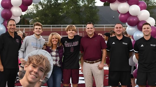 Estudiantes y adultos de la Ballard High School se reúnen frente a un edificio con globos para un evento escolar.