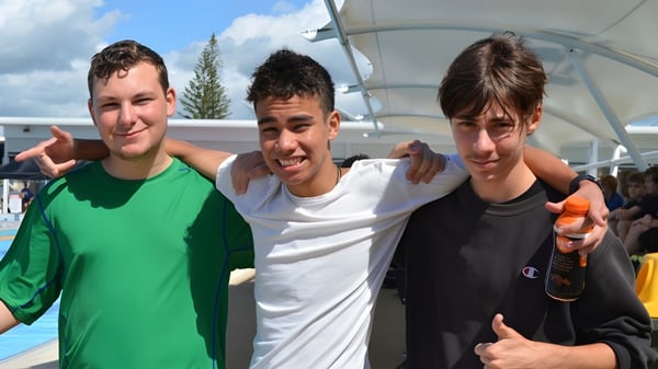 Tres estudiantes están juntos al aire libre en el campus de la Ballina Coast High School.