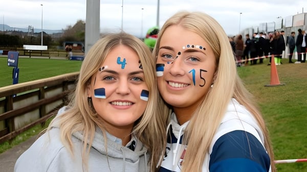 Dos alumnas de la Bandon Grammar School con caras pintadas en un evento deportivo al aire libre.