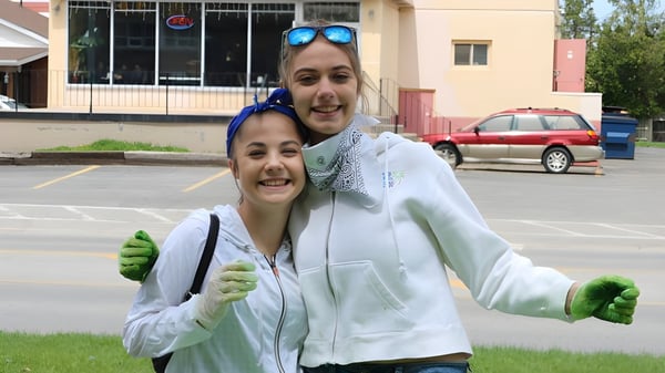 Dos estudiantes de la Banting Memorial High School están frente a un edificio con coches estacionados de fondo.