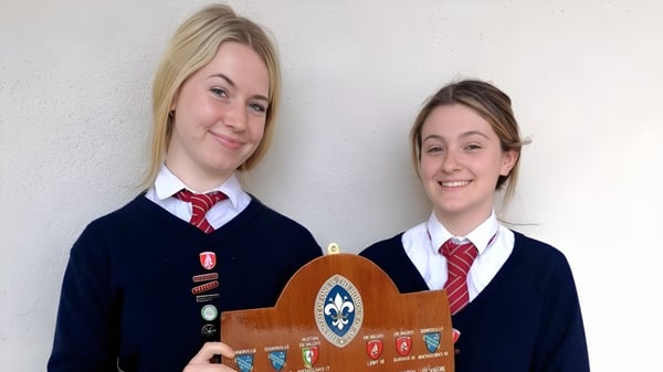 Dos estudiantes sonríen frente a una pared blanca en el Bantry Community College.