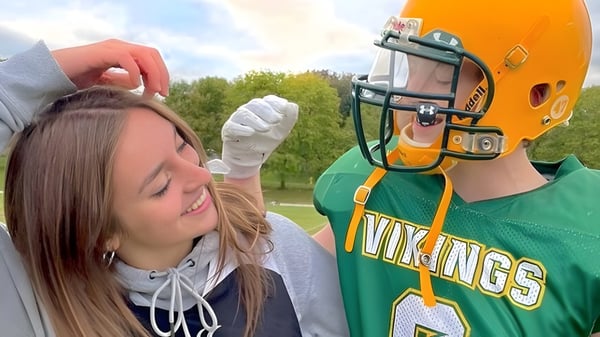Una persona con una camiseta verde de los Vikings de deporte está junto a otra persona en el terreno del Barrie North Collegiate Institute.