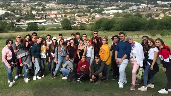 Un grupo de estudiantes de la Bath Academy se reúne en un campo con vista a una ciudad en el fondo.