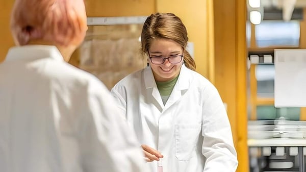 Una joven en una bata de laboratorio blanca sonríe en el laboratorio de la Bath Academy.