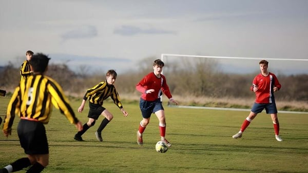 Un grupo de estudiantes juega al fútbol en el campo deportivo de la Battle Abbey School bajo un cielo nublado.